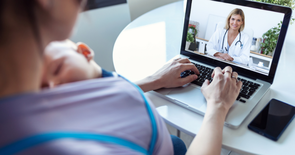 woman wearing an infant in a wrap, while video conferencing with a medical professional