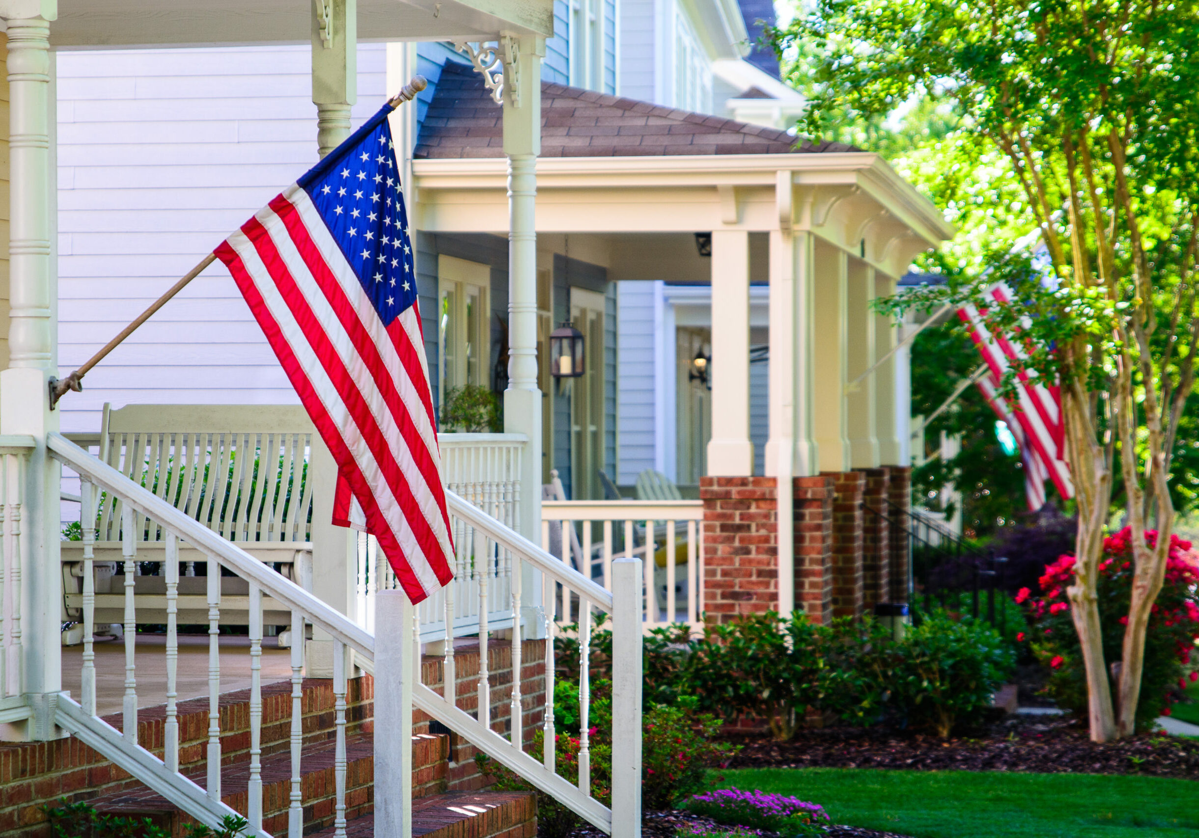 A line of suburban homes display large American Flags